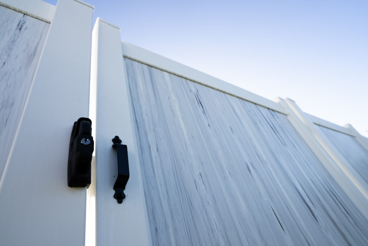 Primer plano de una puerta de valla de vinilo blanco con bisagras y herrajes de pestillo de alta resistencia